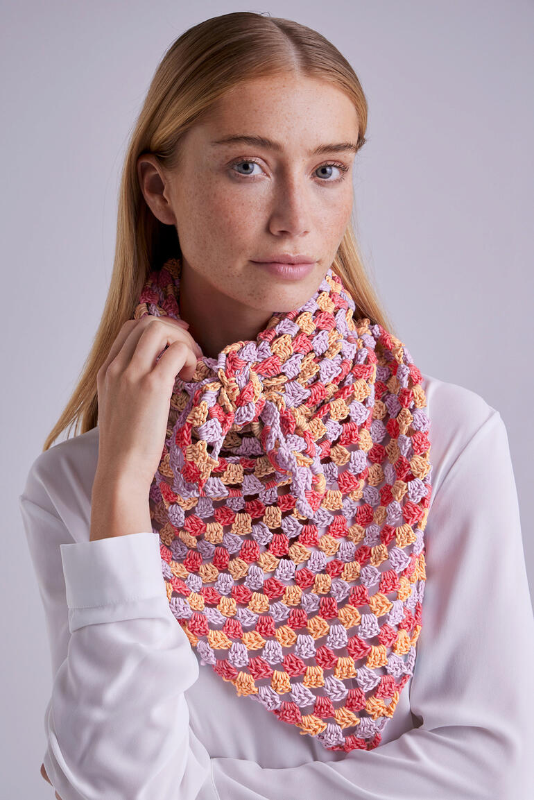 Gehaekeltes Dreiecktuch in bunten Farben, getragen von einer Frau mit blonden Haaren.