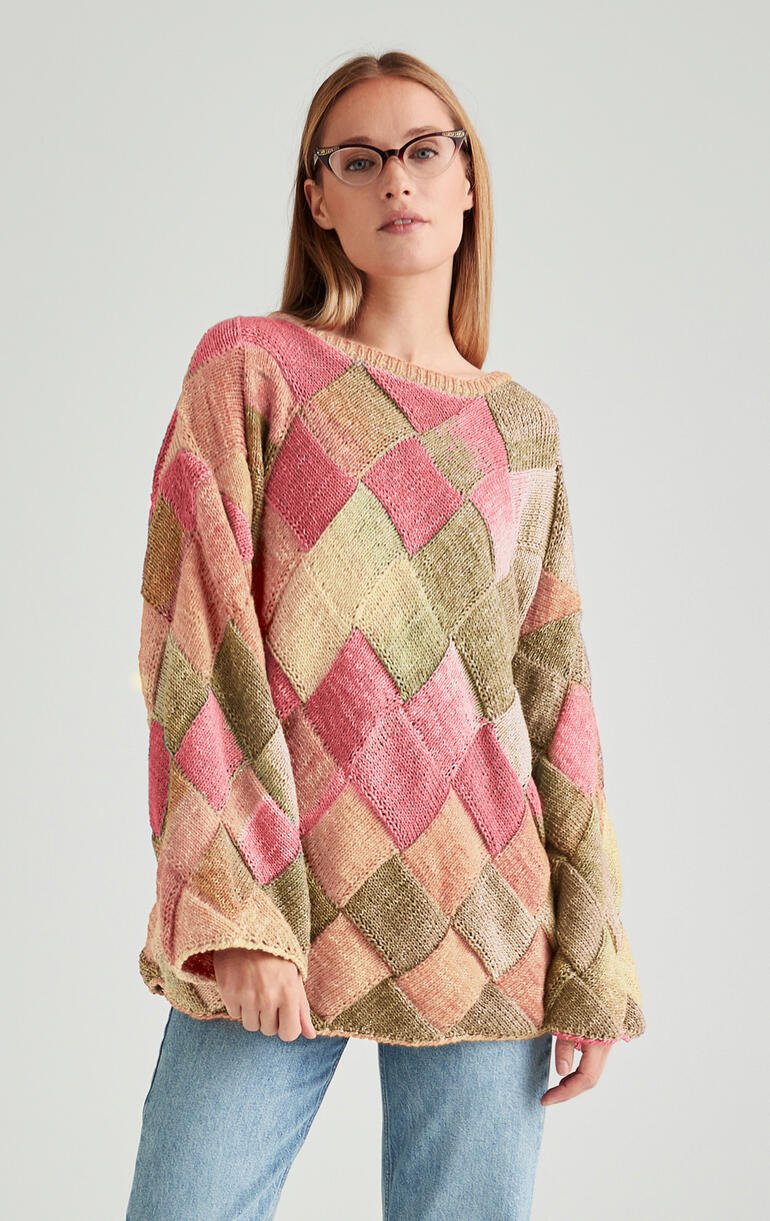 Oversize-Pulli in buntem Rautenmuster, getragen von einer Frau mit langen Haaren.