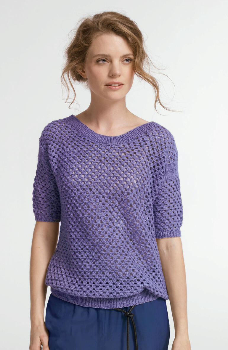 Luftiger Pullover in lila, mit kurzen Ärmeln, getragen von einer Frau mit lockigen Haaren.