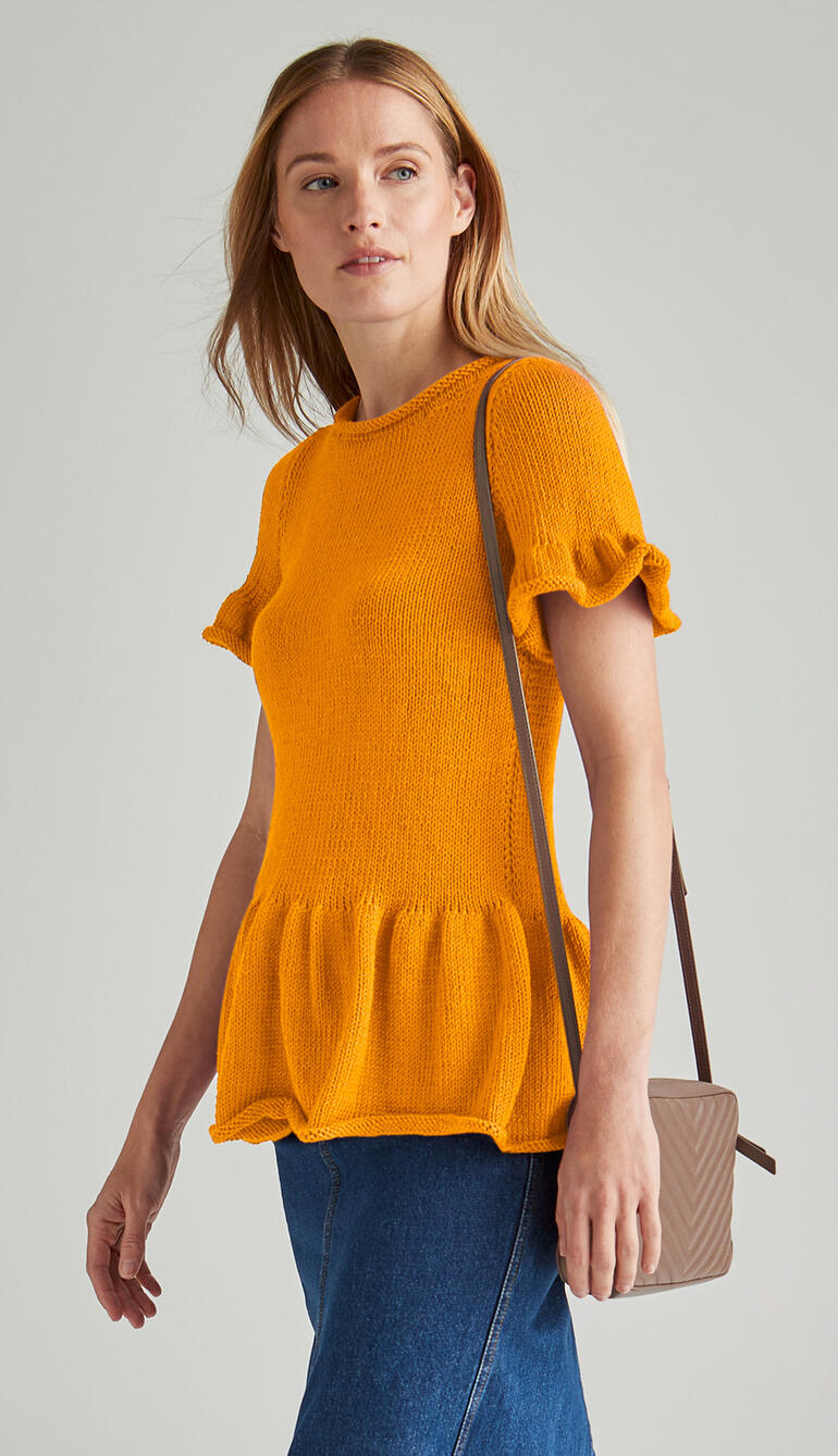 Gelber Pulli mit Rüschensaum, getragen von einer Frau mit langen, glatten Haaren.
