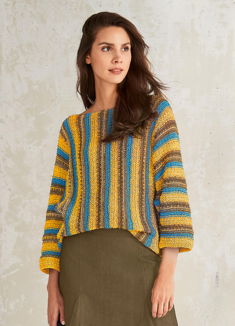 Bunter Fledermausärmel-Pullover mit variierenden Farben, getragen von einer Frau mit langen Haaren.