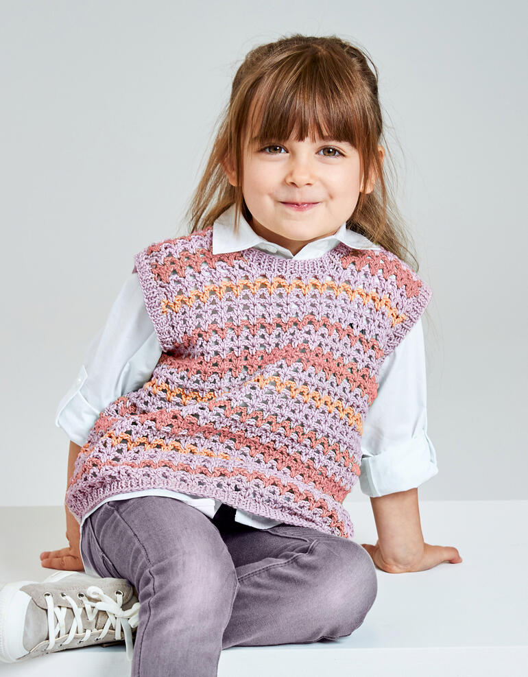 Bunter Kinderpullunder aus Recyclingmaterial, getragen von einem lächelnden Mädchen.