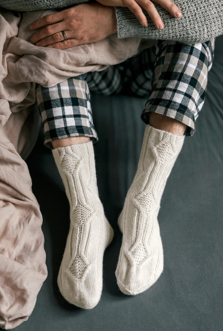 Füße in cremefarbenen Socken auf einem bequemen Sofa.