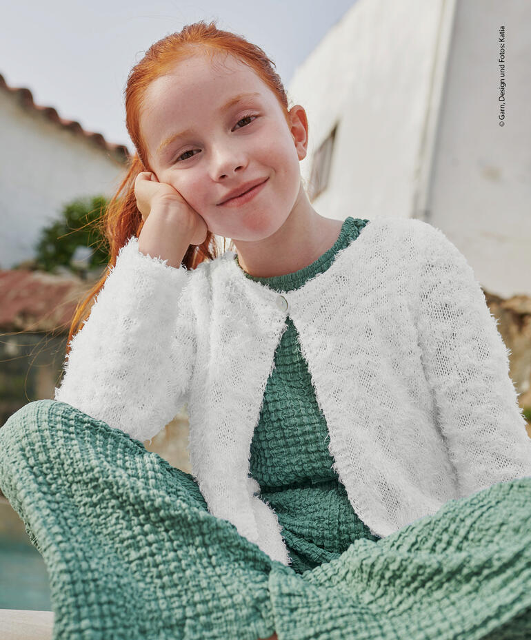 Weiße Kinderjacke aus Bel-Air, getragen von einem Mädchen mit langen roten Haaren.