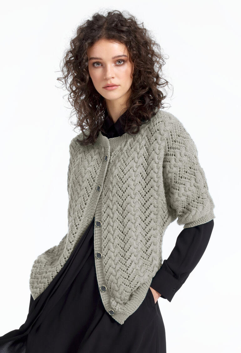 Frau in einer grauen Jacke aus Babyboomer, lächelnd, in schwarzem Kleid