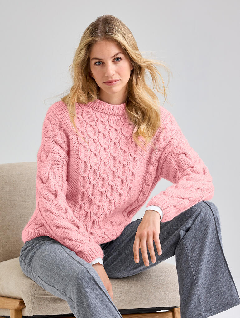 Frau in rosa Pullover aus Canoso, sitzt lässig auf einem Stuhl