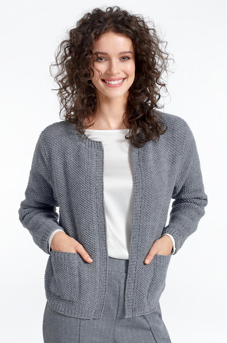 Frau in grauer Merino-Extrafein Jacke, lächelnd, mit Taschen