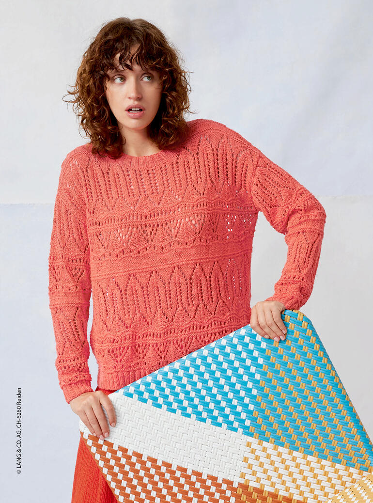 Frau in einem lockeren Pullover aus Ananas von LANG Yarns, hält einen bunten Teppich.