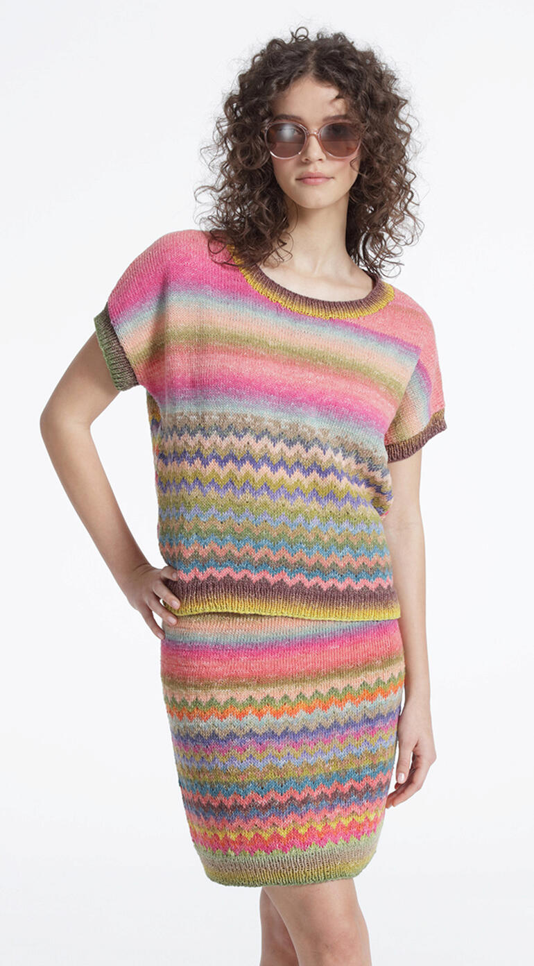 Frau in bunt gestreiftem Kleid mit Kurzärmeln posiert mit Sonnenbrille.