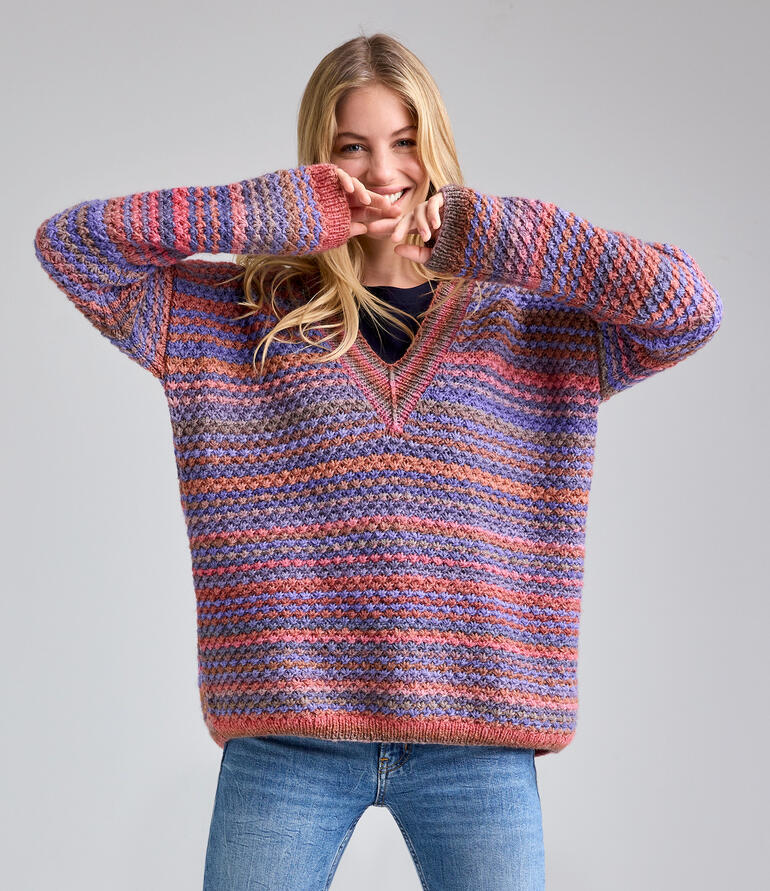 Frau in einem bunten Pullover aus Batique, spielt und lächelt