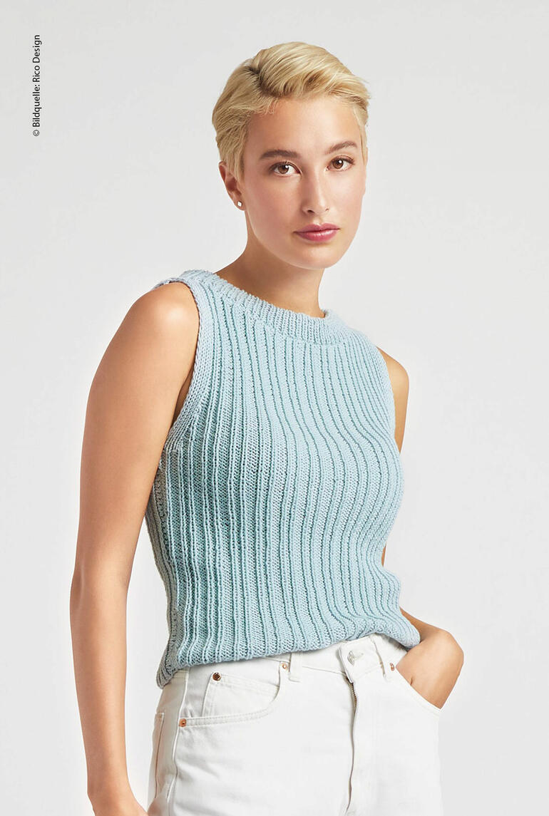 Blonde Frau in aquafarbenem, ärmellosem Top mit Rippenstruktur, posiert in hellem Raum.