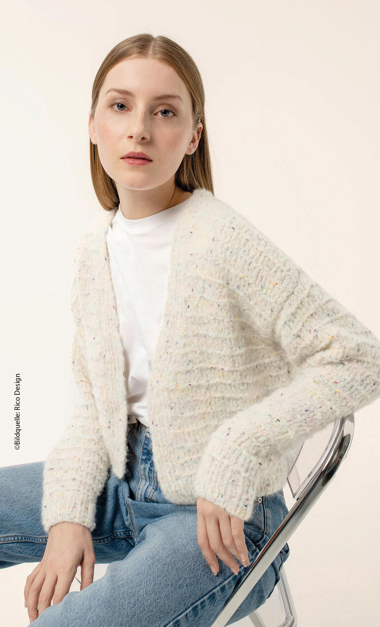 Frau in heller, gestreifter Jacke, weißem T-Shirt und blauen Jeans sitzt im Sessel.