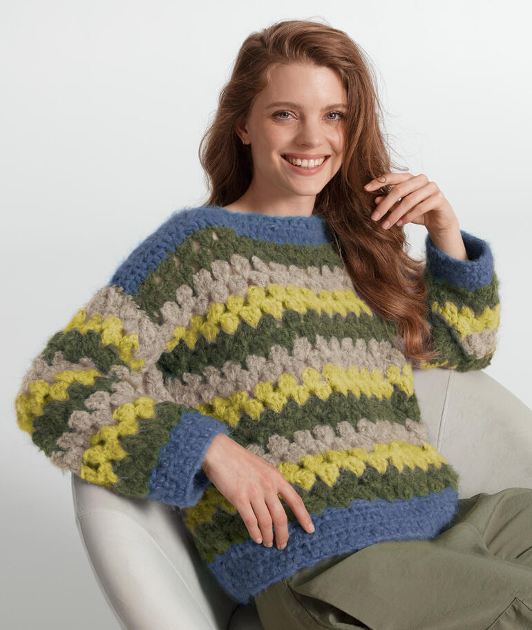 Bunter Häkelpullover von Junghans-Wolle, weibliches Model lächelt.