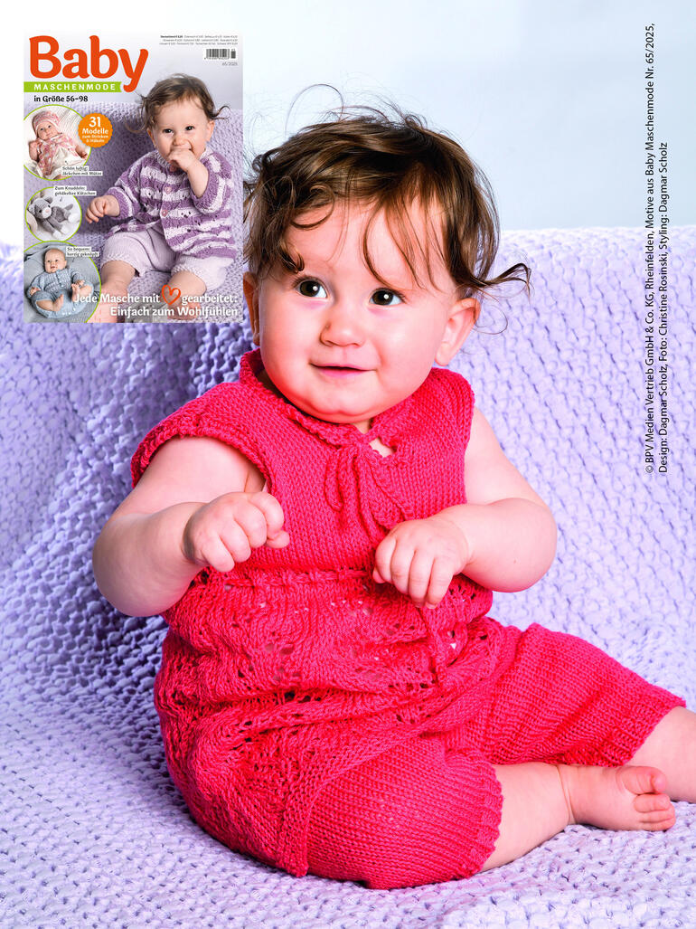 Kleines Mädchen in einem rosa Kleid mit Leggings, lächelt auf einer Decke.