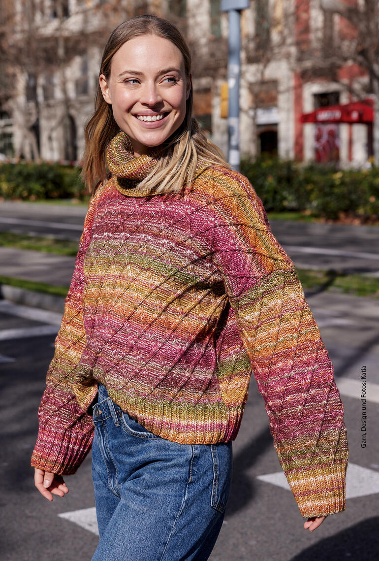 Frau in gemustertem Pullover aus Cotton-Merino, voller Lebensfreude, läuft über die Straße.