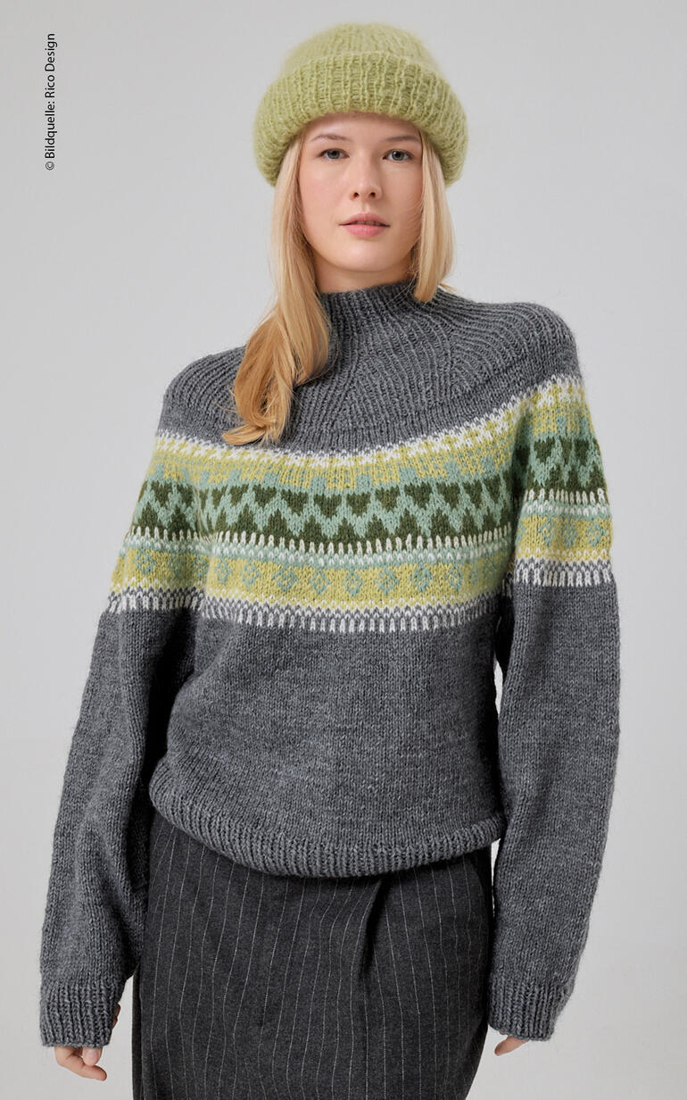 Frau in grauem Pullover mit grünem Muster, trägt einen grauen Hut.