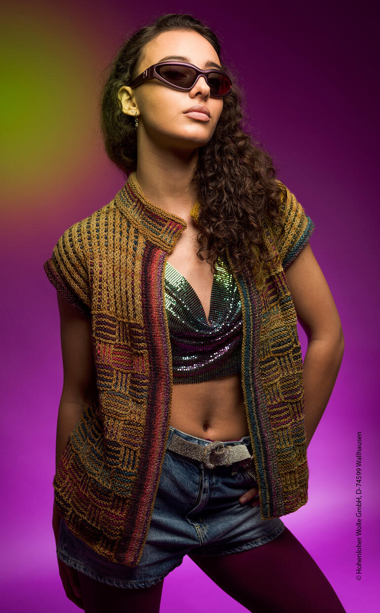 Frau trägt eine bunte Weste, posiert farbenfroh mit Sonnenbrille.