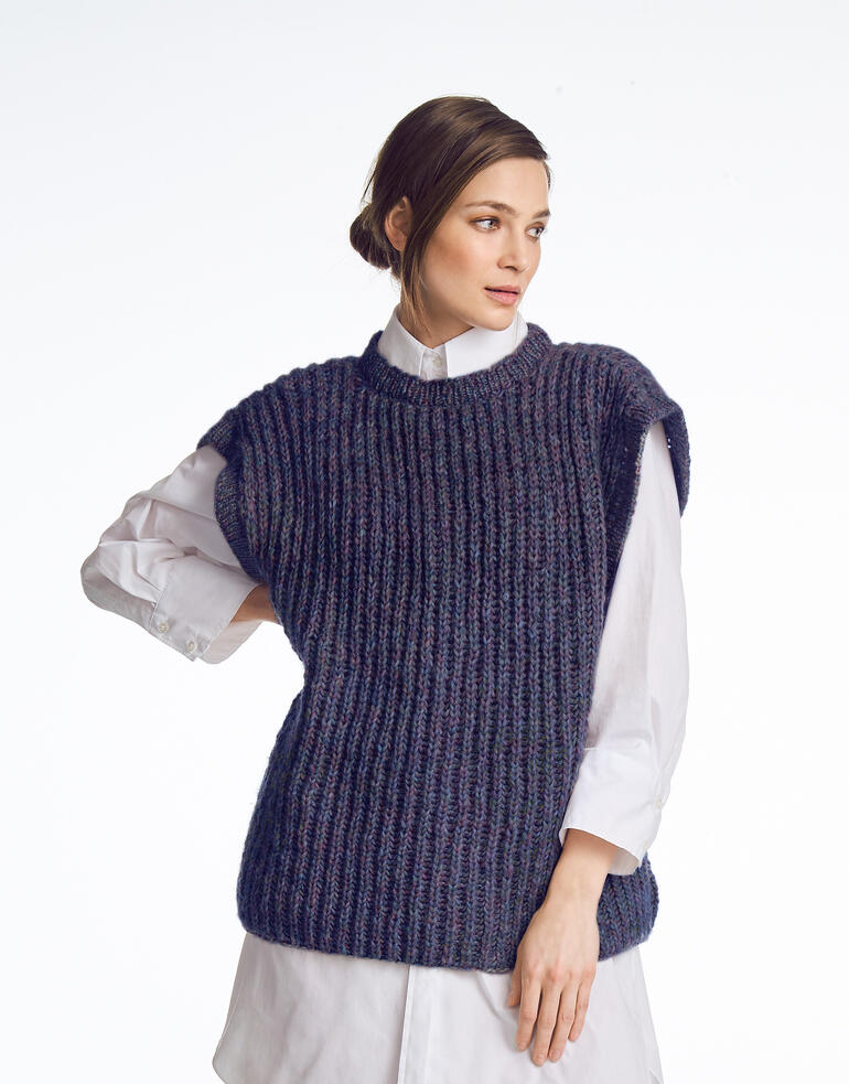 Frau in einem dunkelblauen Pullunder, trägt ein weißes Hemd darunter.