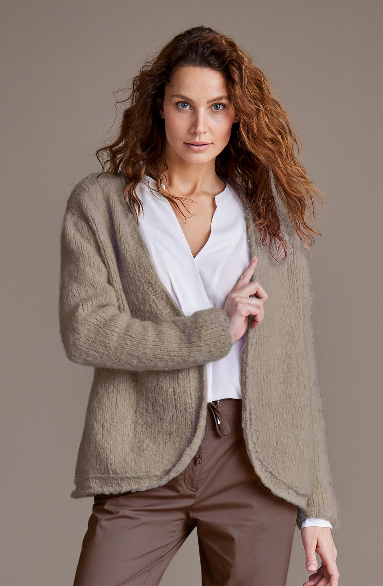 Junge Frau trägt eine beigen Jacke aus Nappy von Junghans-Wolle.