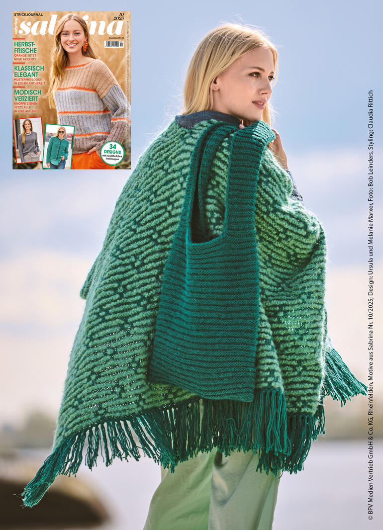 Frau mit Poncho und Tasche aus Nappy, vor einer hellen Landschaft.