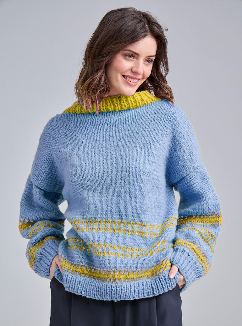 Frau trägt einen graublauen Pullover aus NewWool von Junghans-Wolle