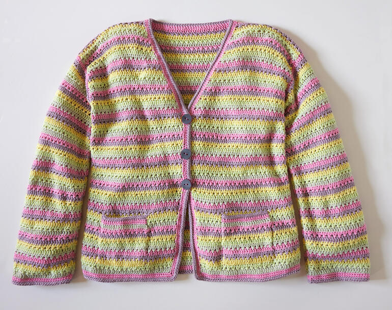 Häkeljacke aus Brillianto in bunten Streifen mit Knöpfen vorne.