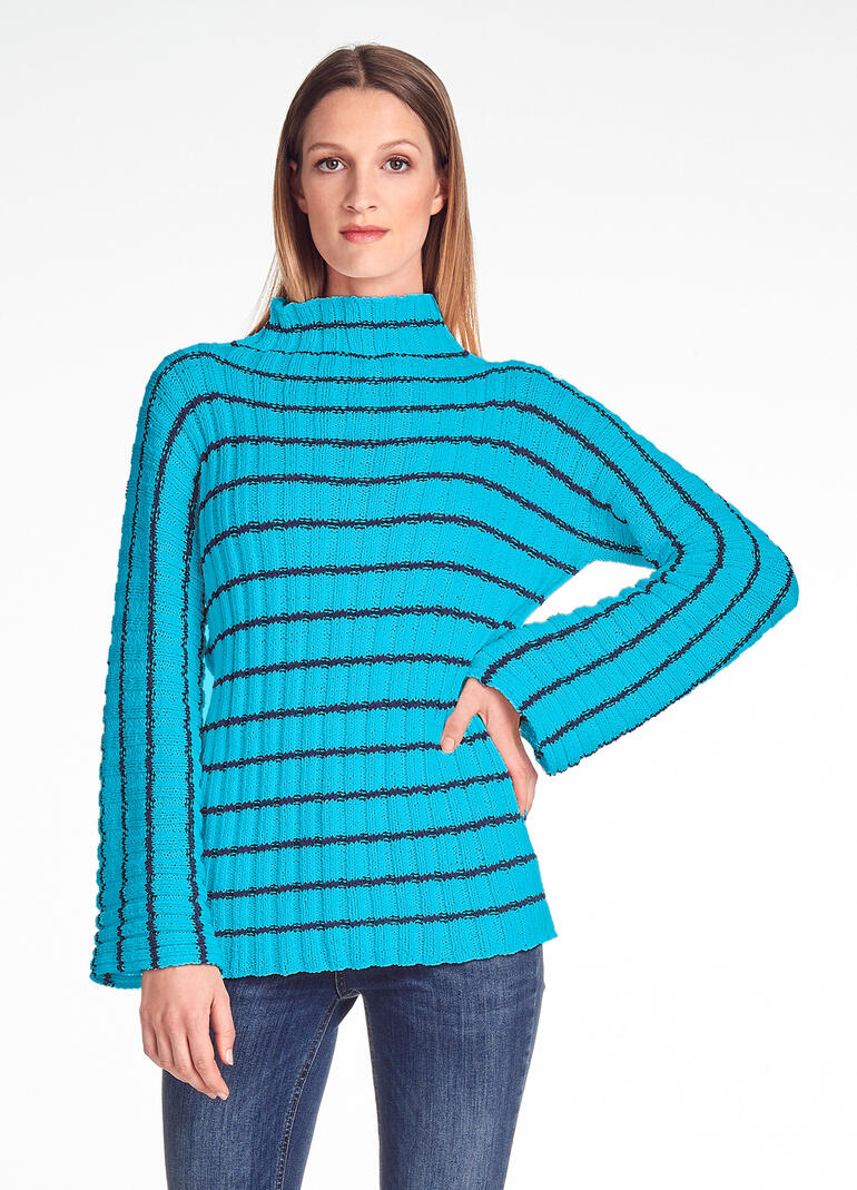 Frau in gestreiftem Pullover aus Cotonia II steht lächelnd.