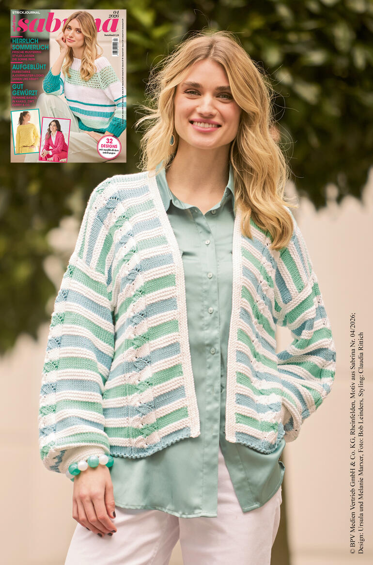 Frau in Ajour-Strickjacke, leicht lächelnd, vor grünem Hintergrund.