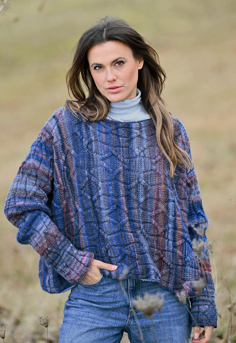 Bunter Quergestrickter Pullover aus Linie 566 Trento, Modell posiert im Freien.