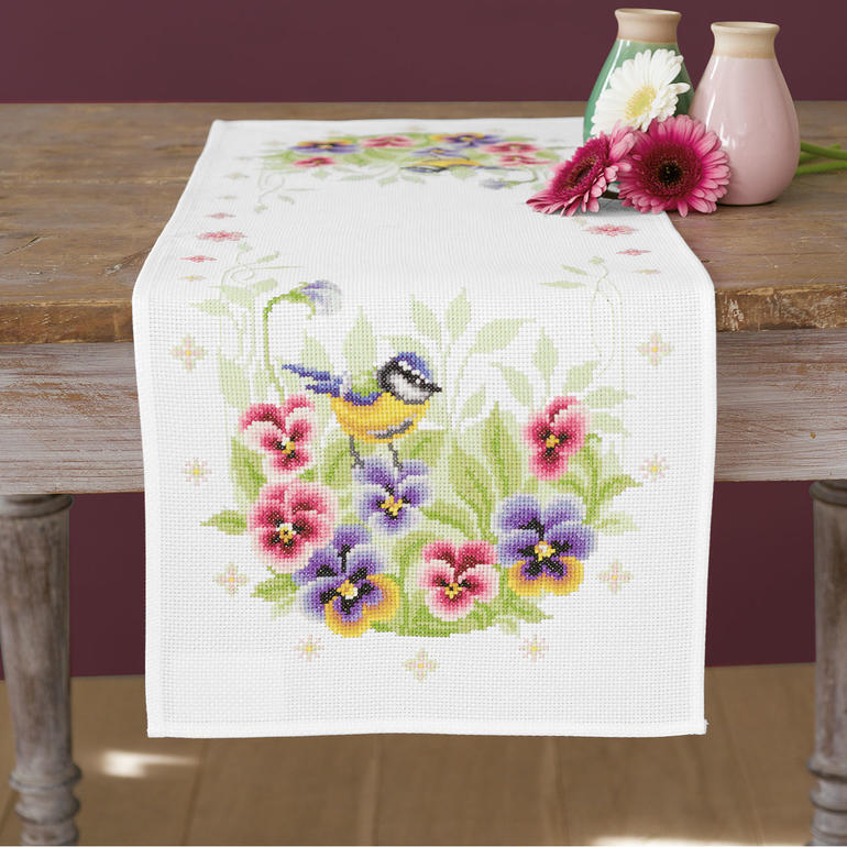 Aida-Tischläufer mit einem Blaumeisen- und Stiefmütterchen-Motiv.