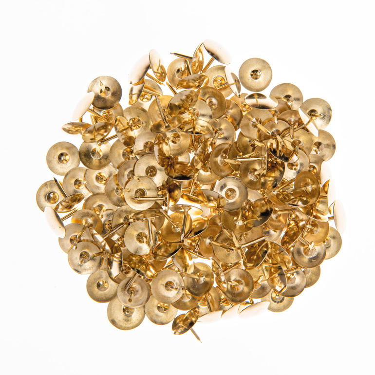 Goldfarbene Reißzwecken in einem Haufen zusammengefügt.