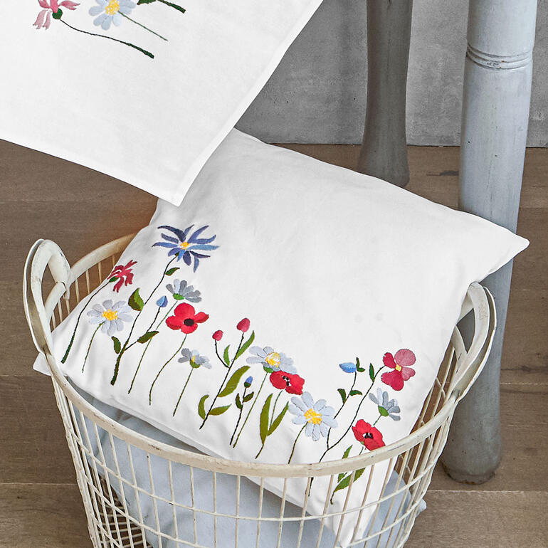 Kissenhülle mit bunten Feldblumen auf weißem Hintergrund