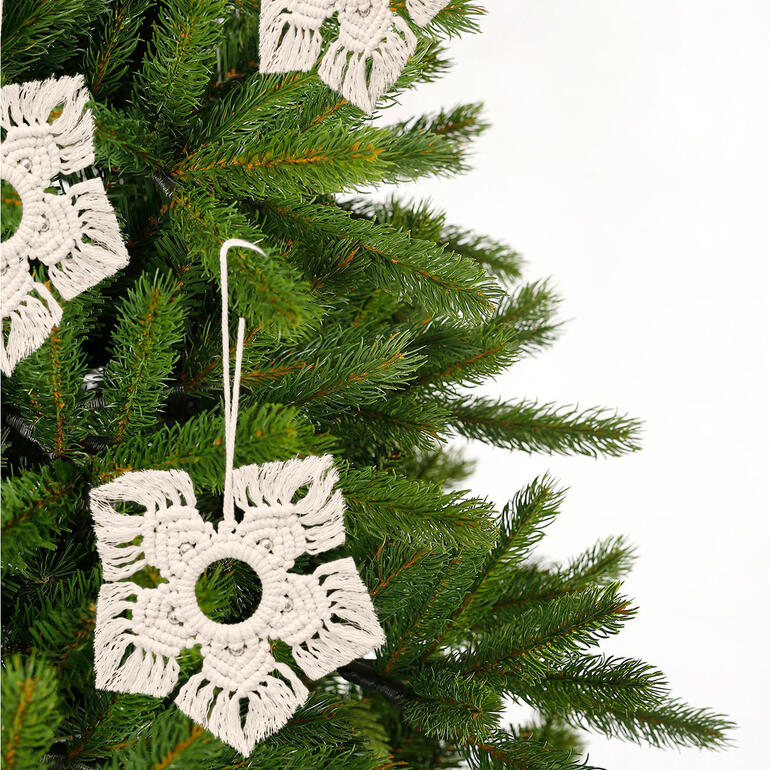 Makramee-Schneeflocken, die an einem Weihnachtsbaum hängen
