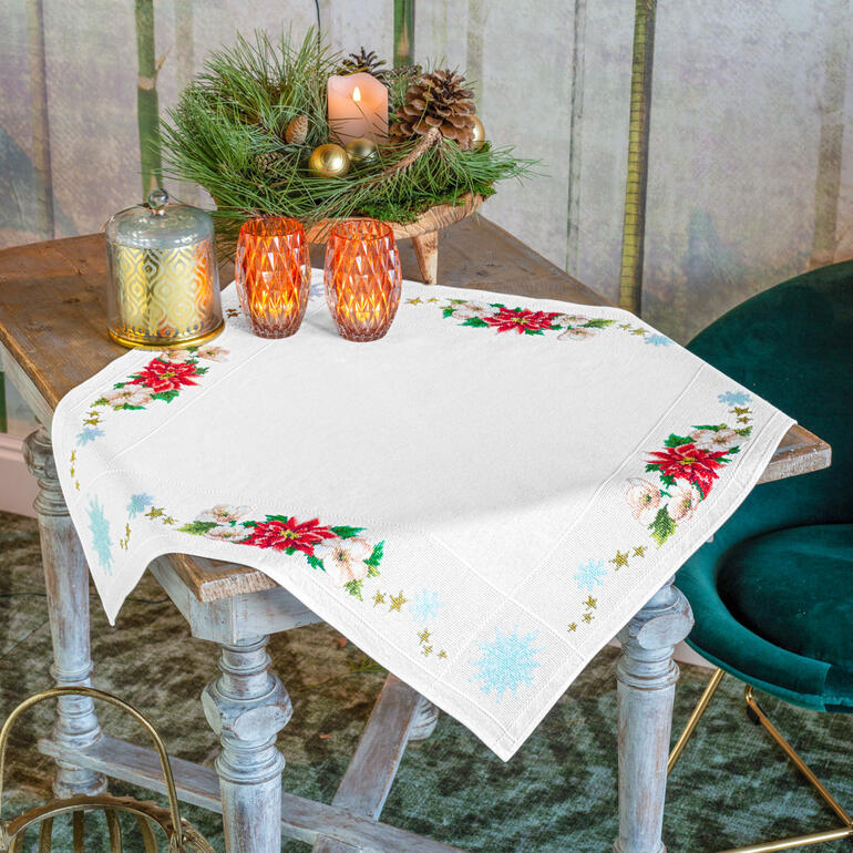 Tischdecke mit Weihnachtsstern und festlicher Dekoration.