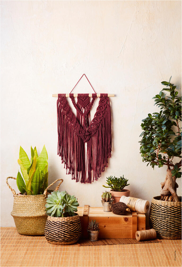 Wandbehang im Boho-Stil aus Makramee mit fransen, hängend an einer Wand.