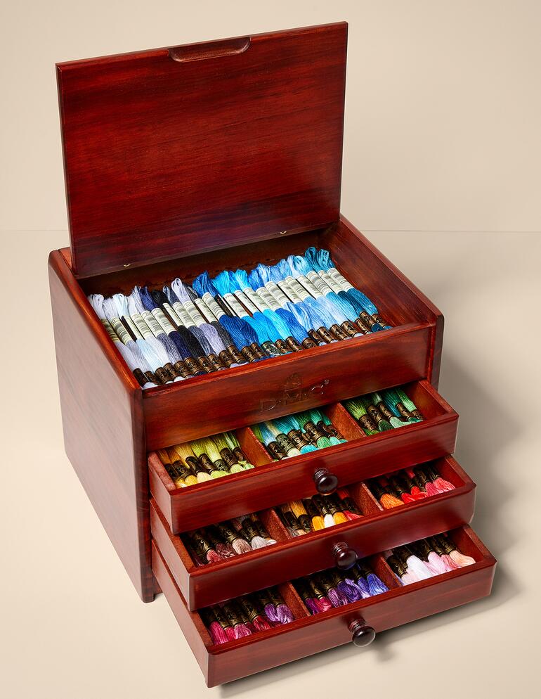 Holzkästchen mit mehreren Schubladen voll mit Stickgarn.
