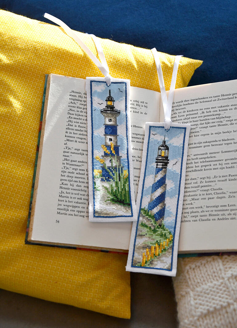 Zwei Lesezeichen mit Leuchttürmen auf einem offenen Buch.