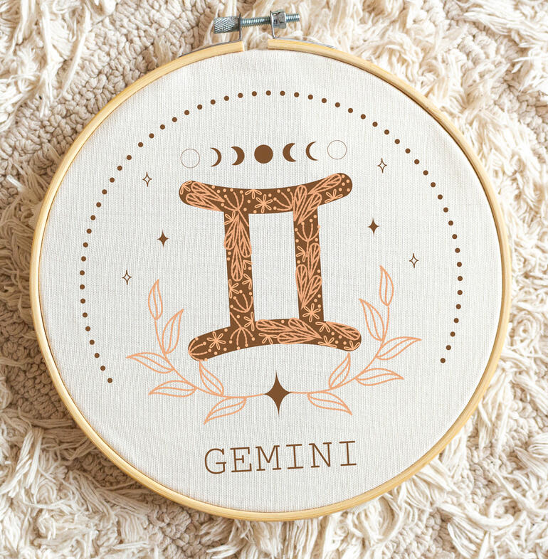 Minimalistische Stickerei des Sternzeichens Zwillinge mit floralen Motiven.