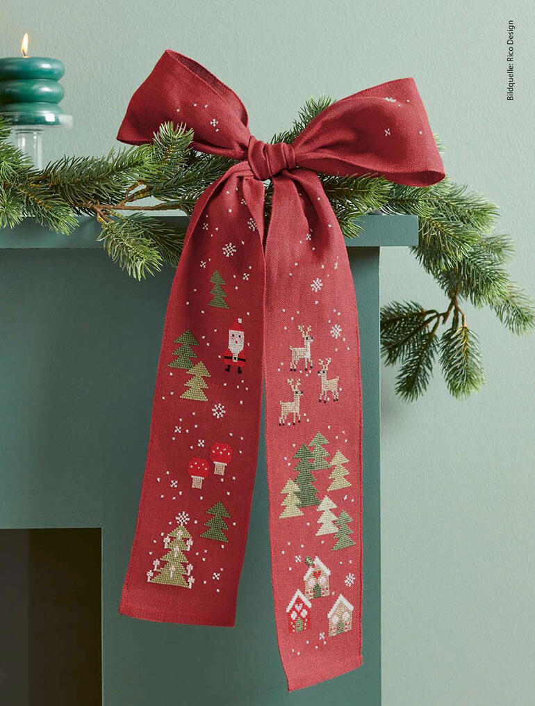 Rote Schleife mit Weihnachtsmotiven hängt dekorativ an einem Kamin