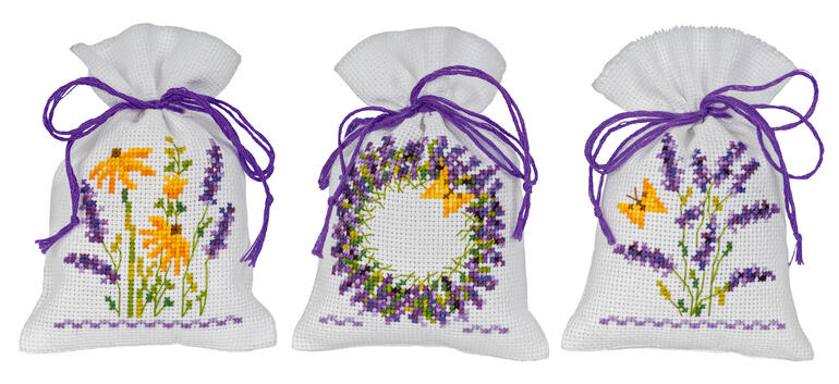 Drei Säckchen mit Lavendel-Motiven, dekoriert mit lila Bändern.